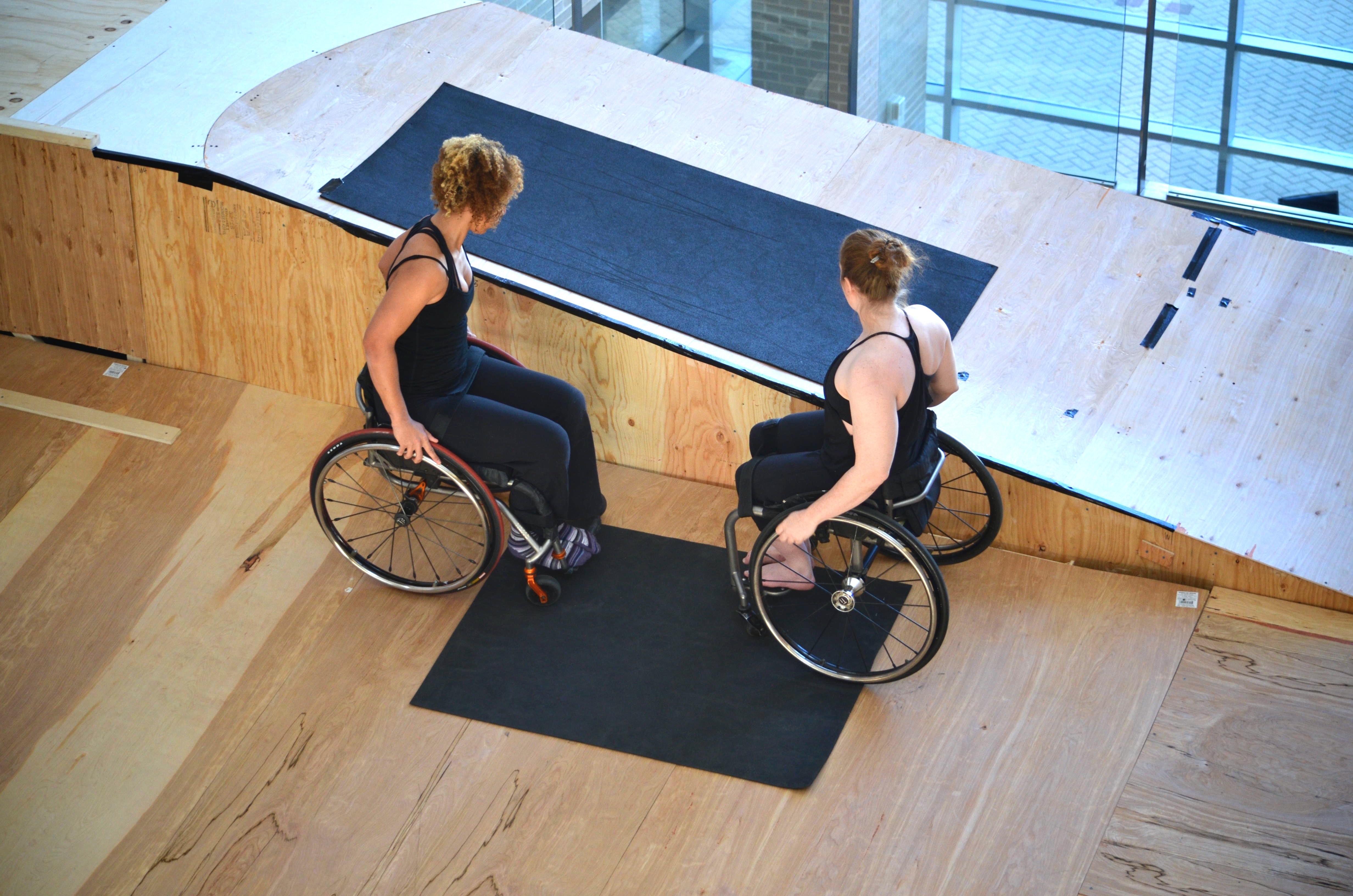 Two women in wheelchairs facing each other, seen from above