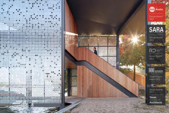 A wooden stairwell next to a metallic looking screen/facade