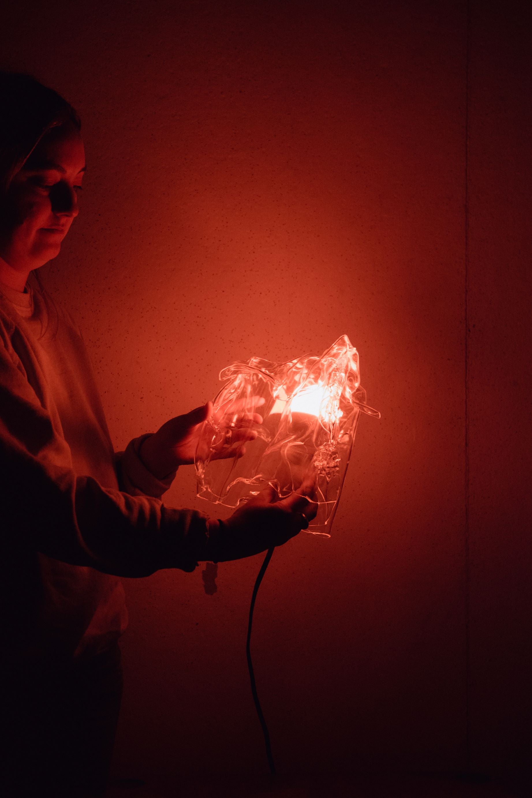 Student awash in red light showing off her lamp creation