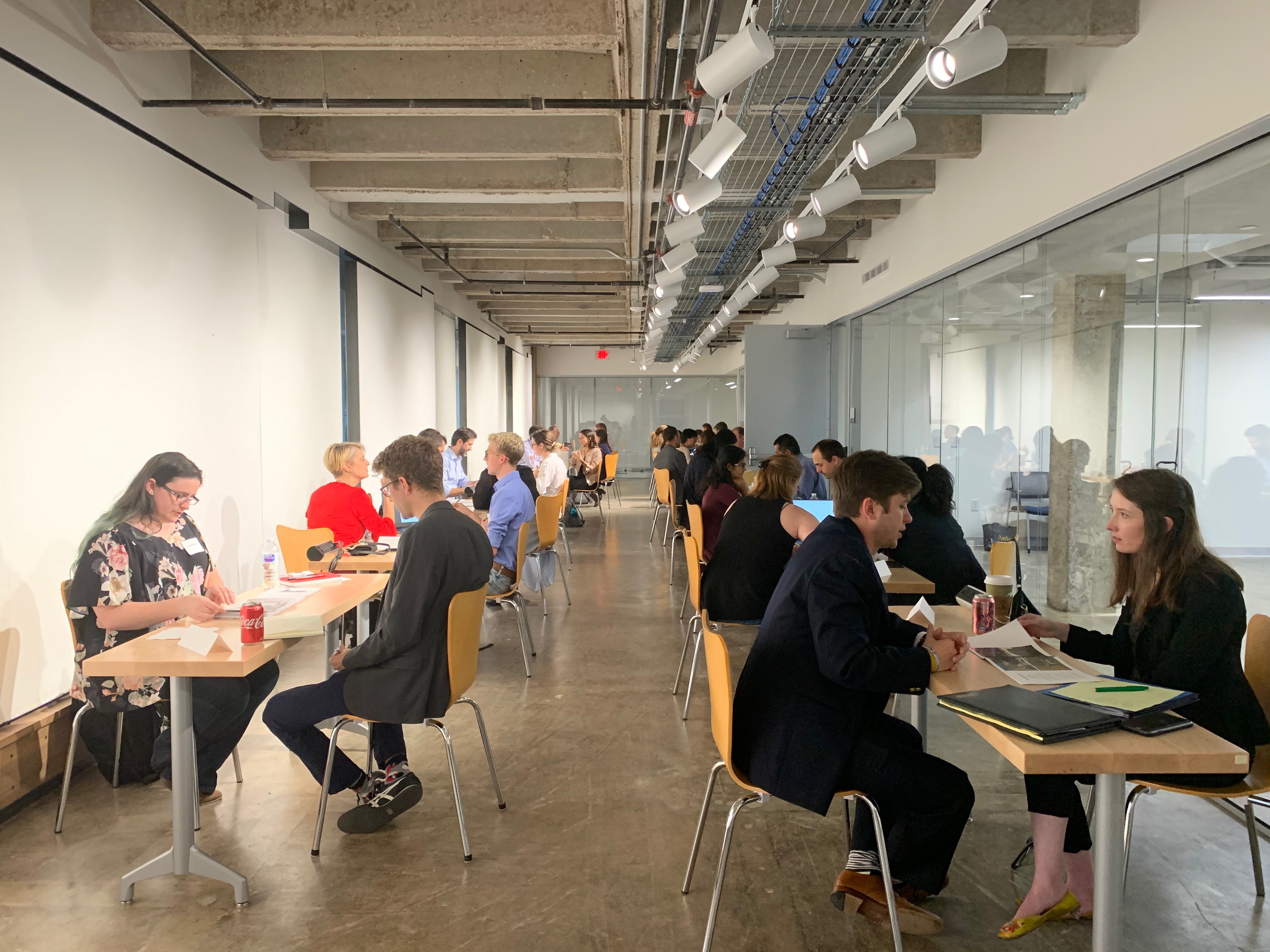 Students and employers sitting at tables set up in two rows along the West Mall Building