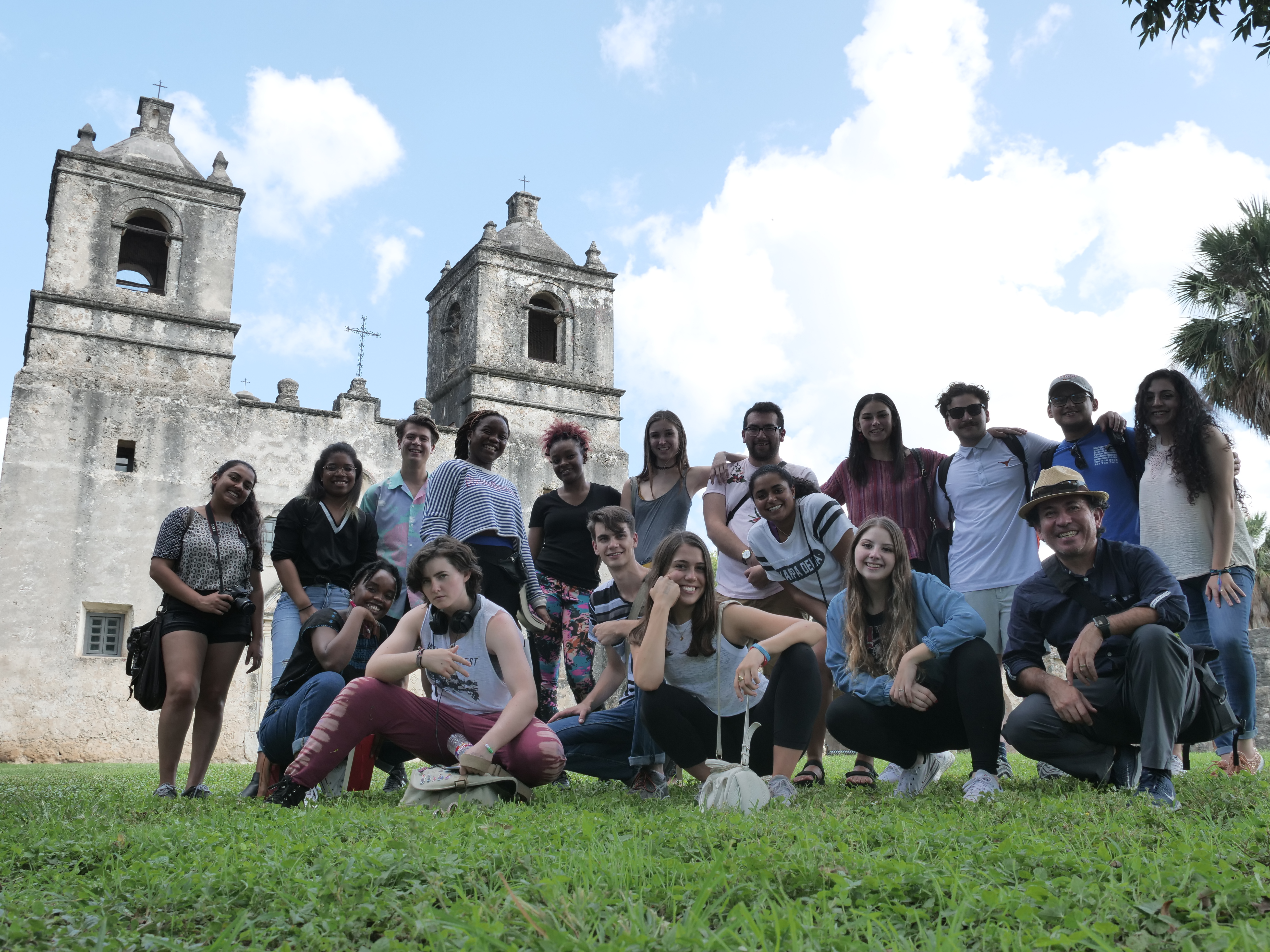 A group of students gathered together with Benjamin Ibarra-Sevilla posing in front of an old Latin American church