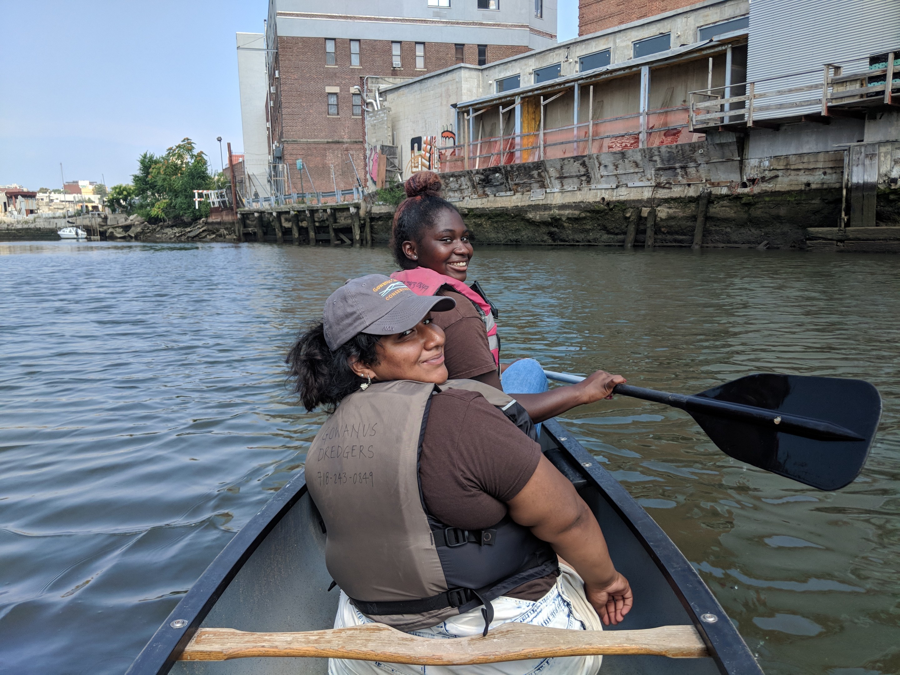 Two women sitting in a kayak looking over their shoulders while smiling at the camera