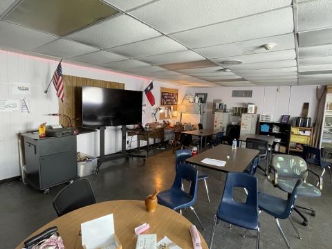 View of the inside of a room with several tables, a TV and U.S. and Texan flags.