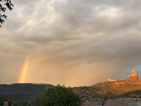 A photo of a rainbow in the sky with a desert, rocky landscape 
