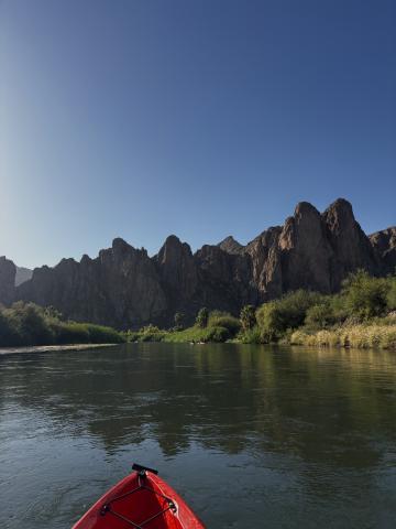 A photo of a canoe in a lake with mountainous landscape in the foreground. 