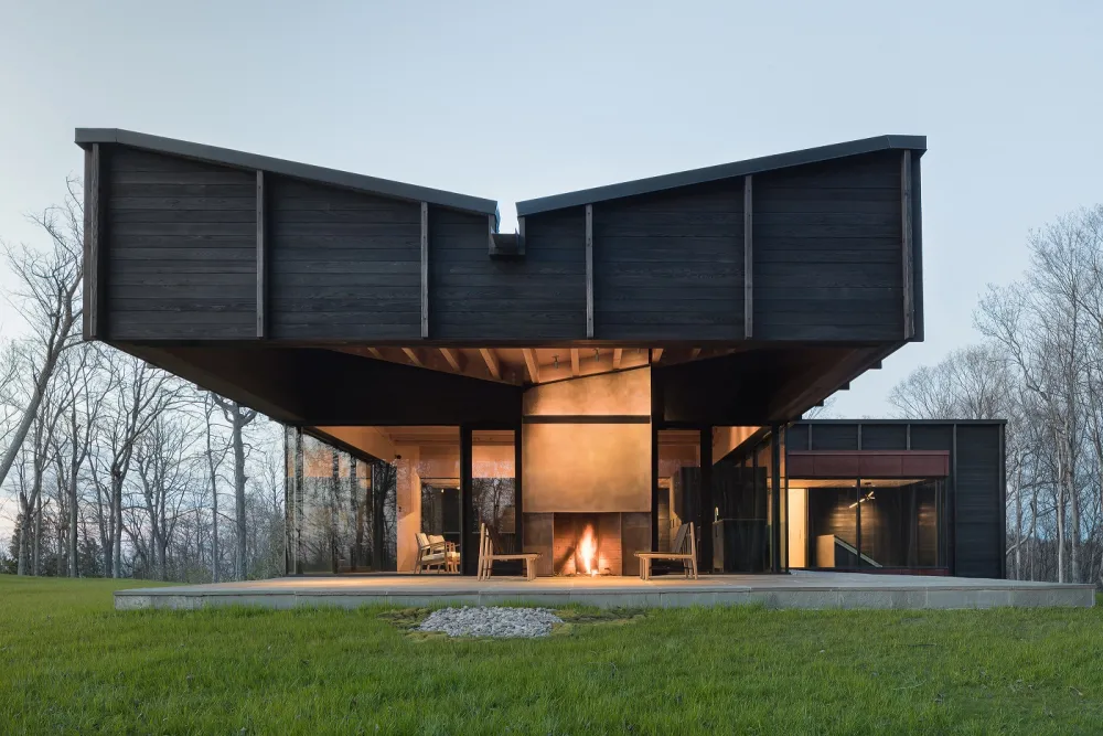 Exterior of a black building at dusk designed by Desai Chia Architecture