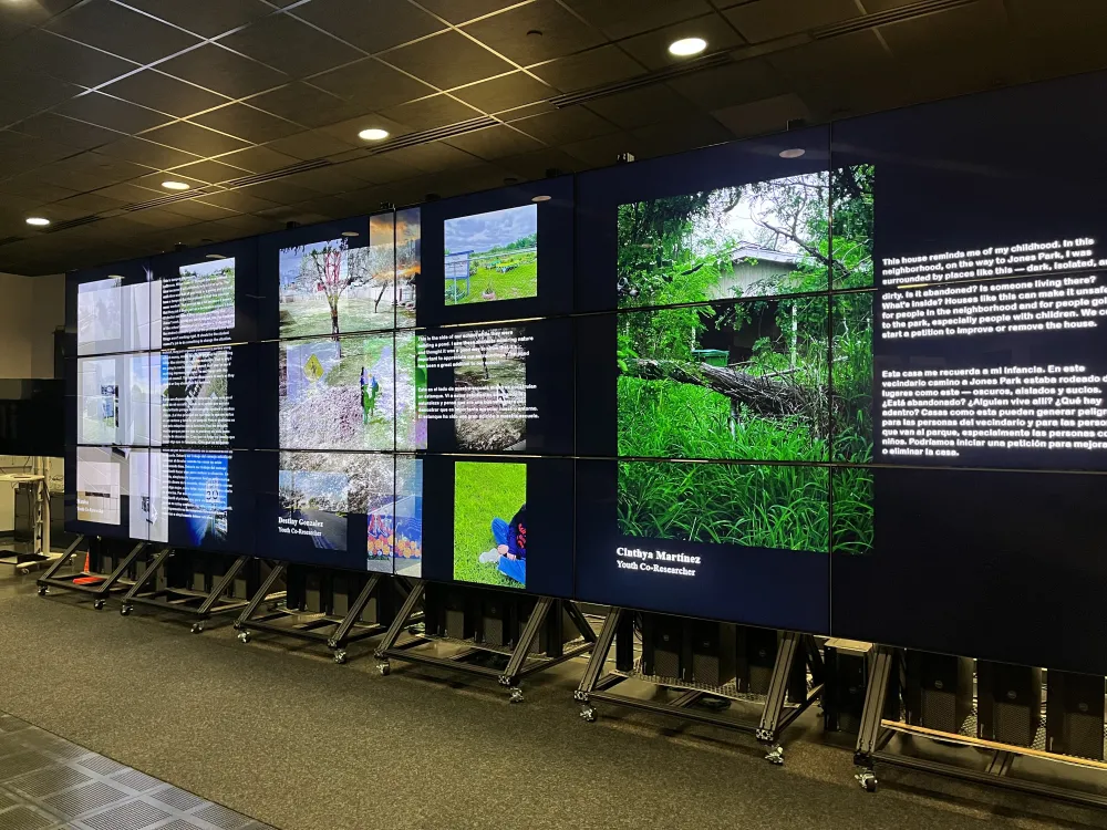 Several screens in a dark room lit up showing photographs as part of the "Looking to the Future" exhibition