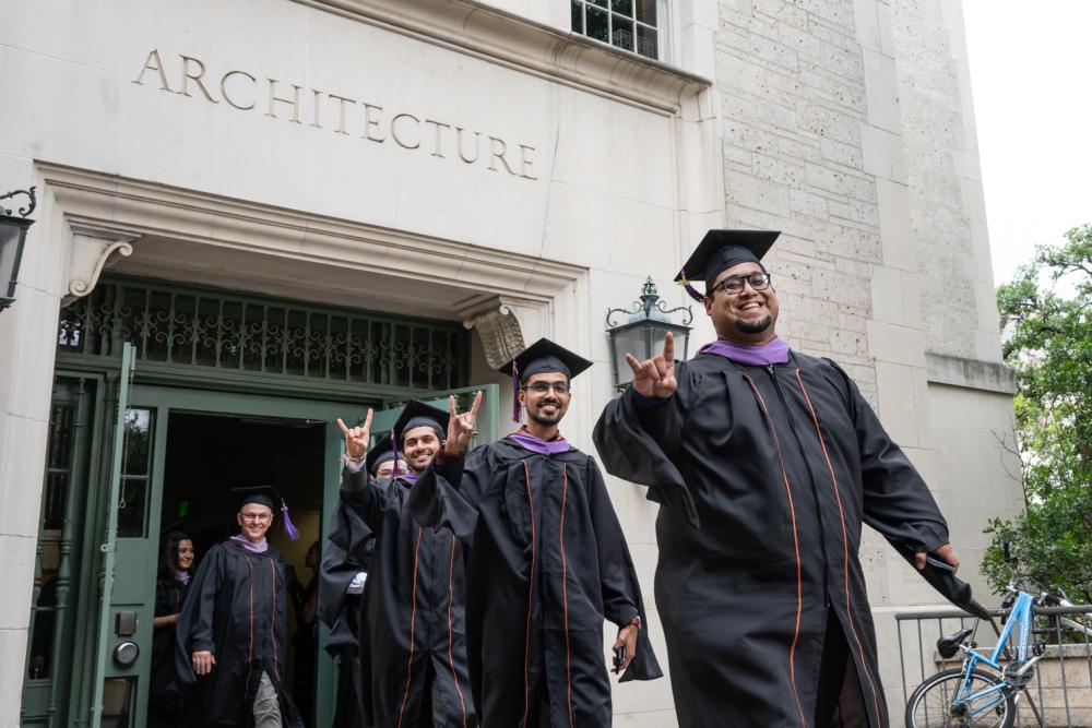 Students in regalia exiting the architecture building.