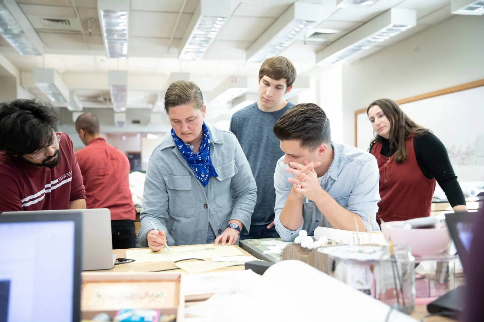Landscape architecture students gather around Assistant Professor Maggie Hansen in studio as she's drawing something out for them