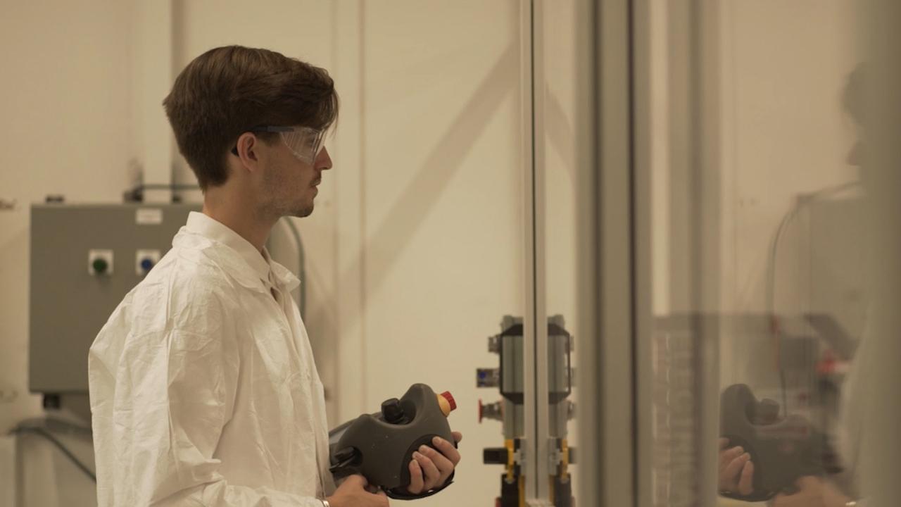 Patrick Danahy wearing protective eyewear looking through glass at something off-screen