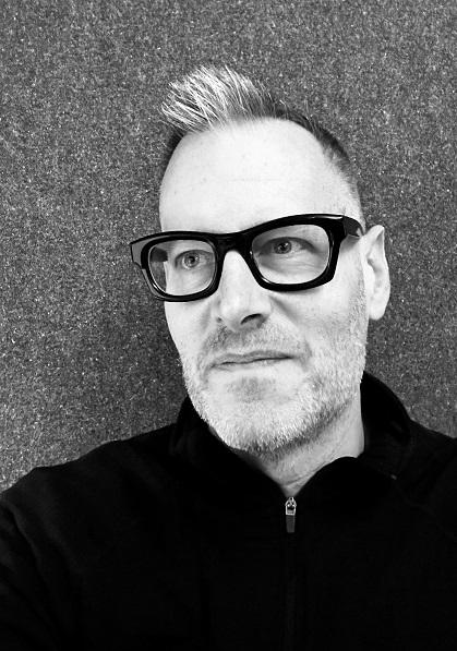 Black and white headshot of the architect Paul Lewis, seen wearing glasses.