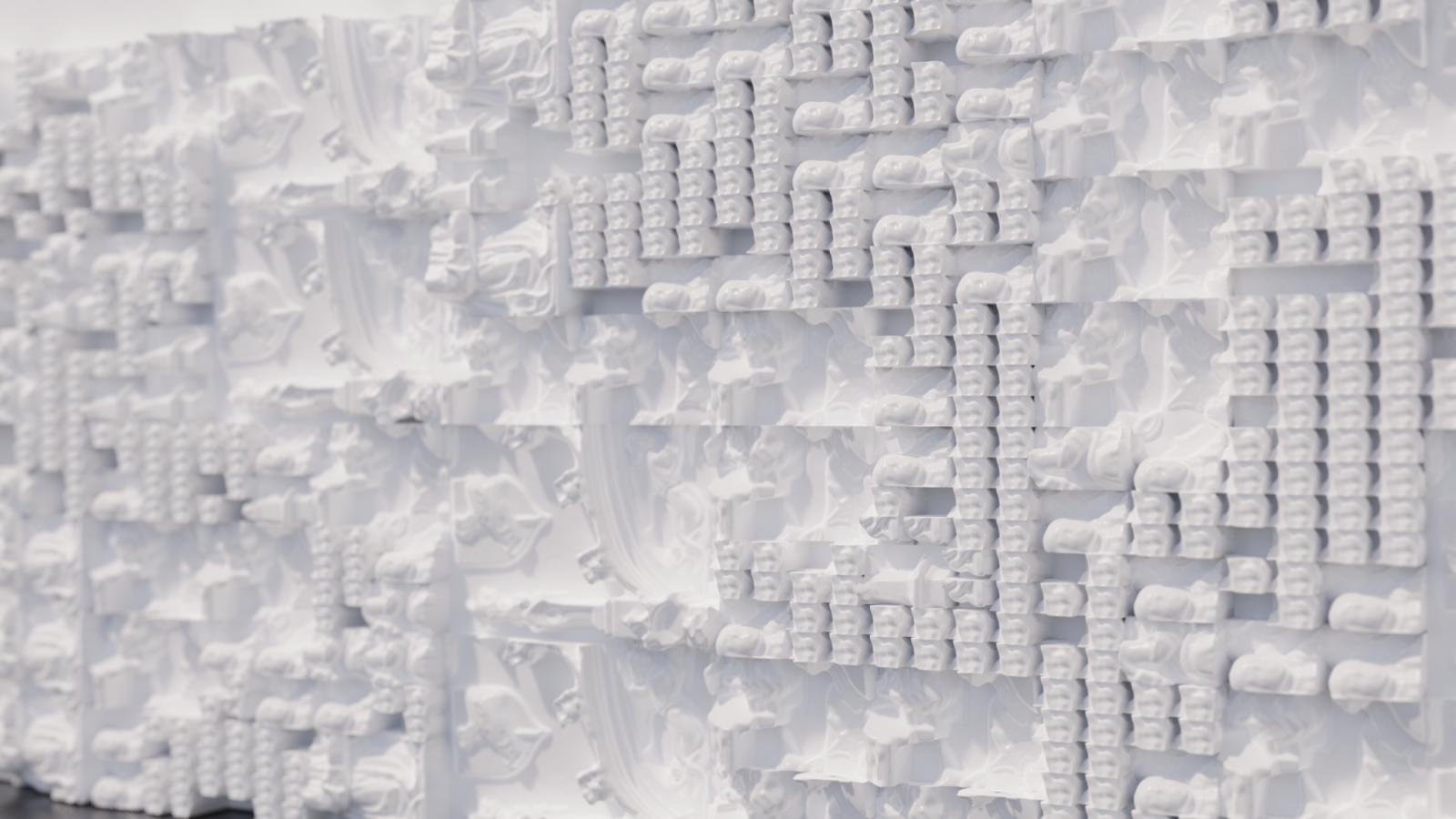 A 3D printed white wall comprised of a series of squares in different groupings.