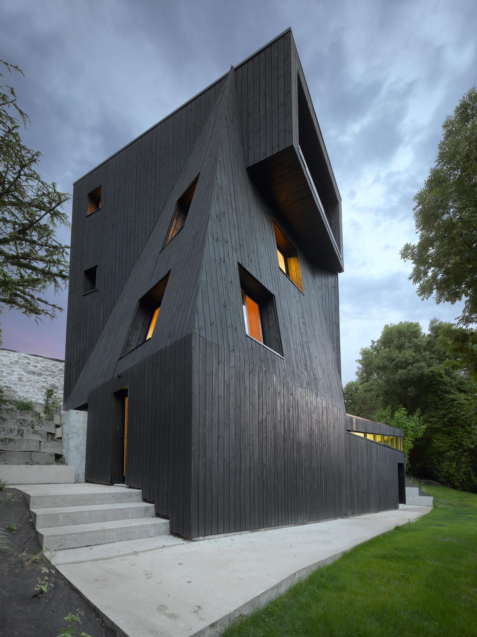 Black angular house with orange lit windows