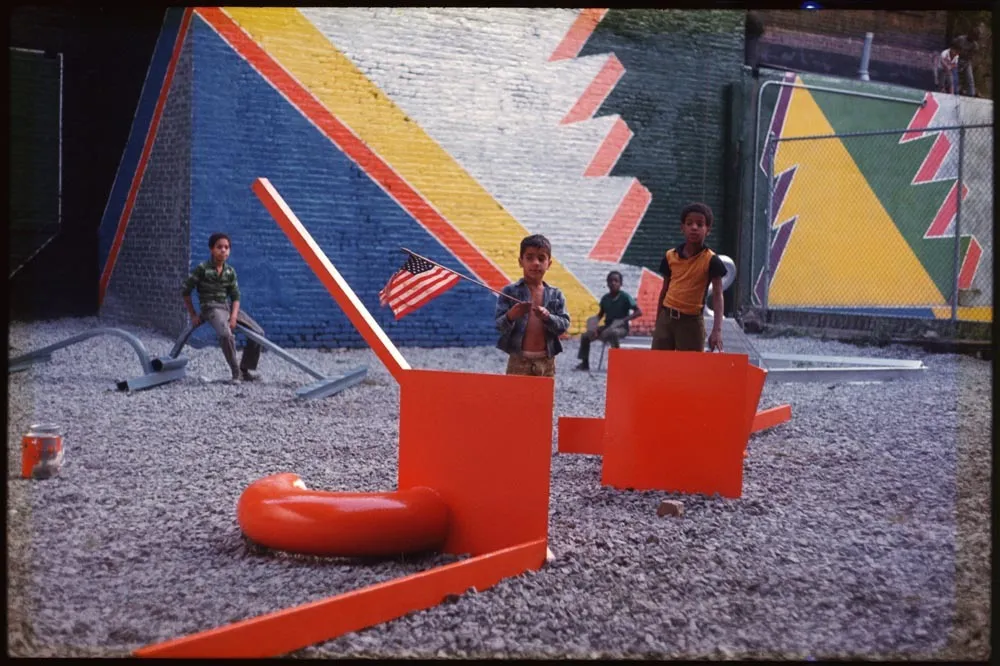 children posing with modern sculptures in front of a mural