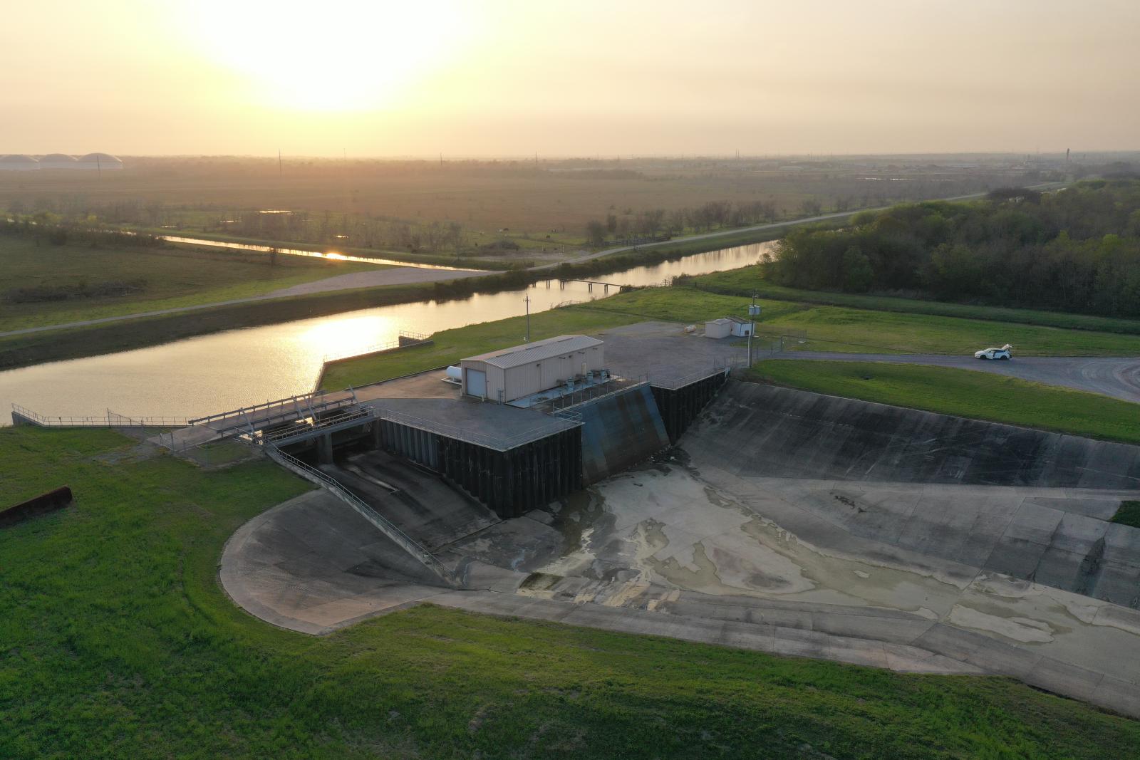 River by a small building connected to a large concrete trough for flooding