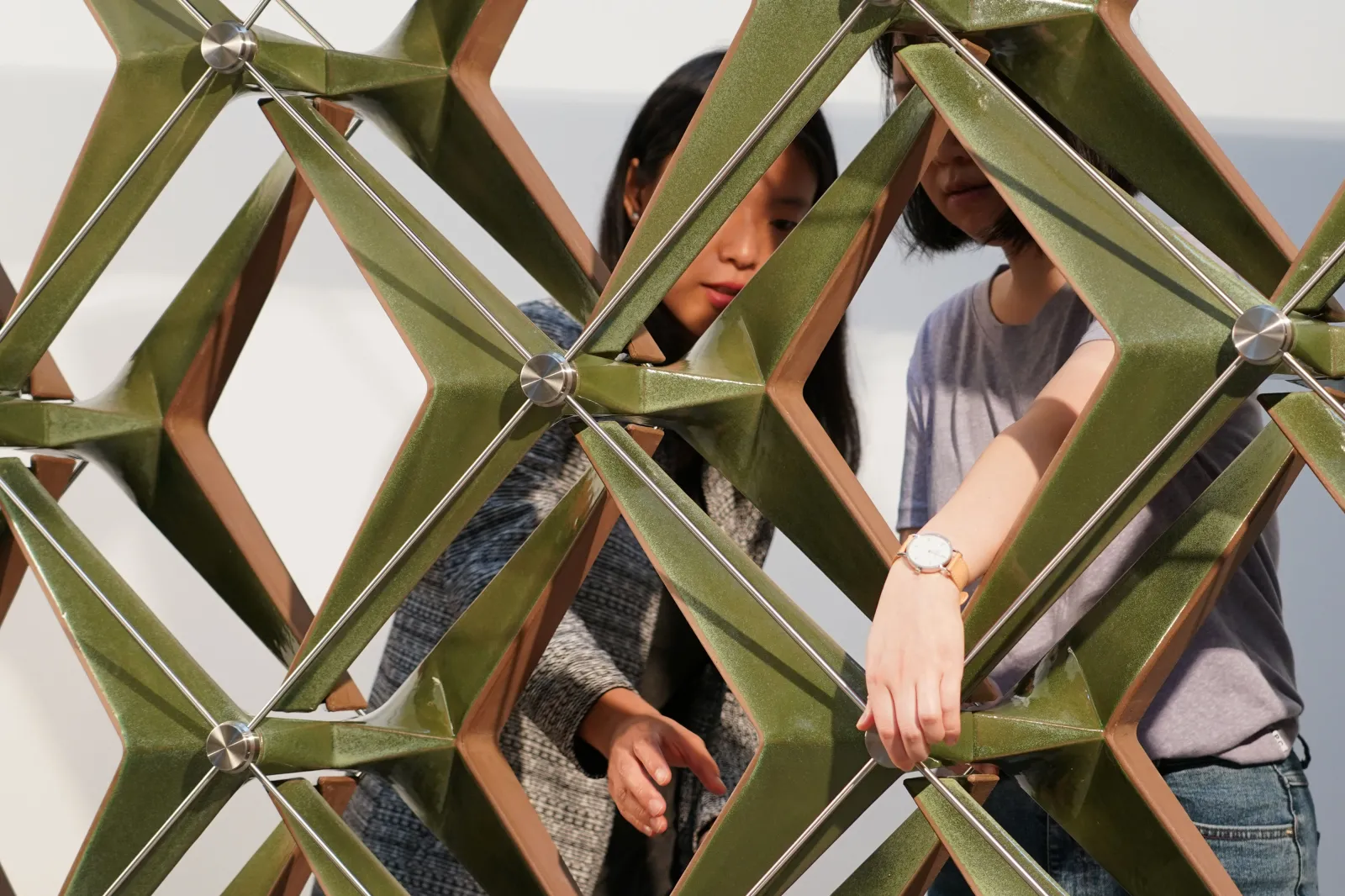 V-Soleil Two people interacting with a metallic, interlocking square structure