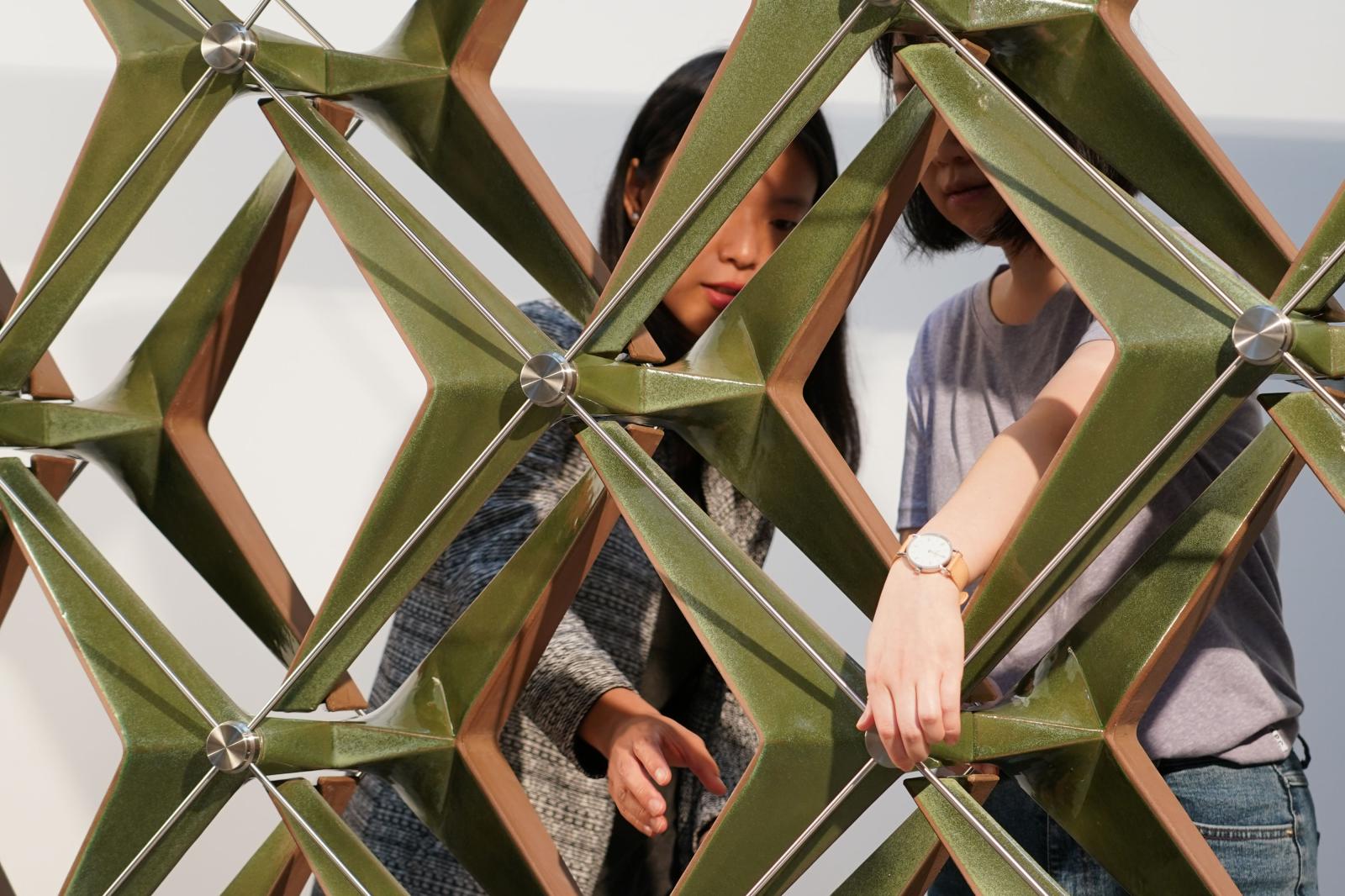 V-Soleil Two people interacting with a metallic, interlocking square structure