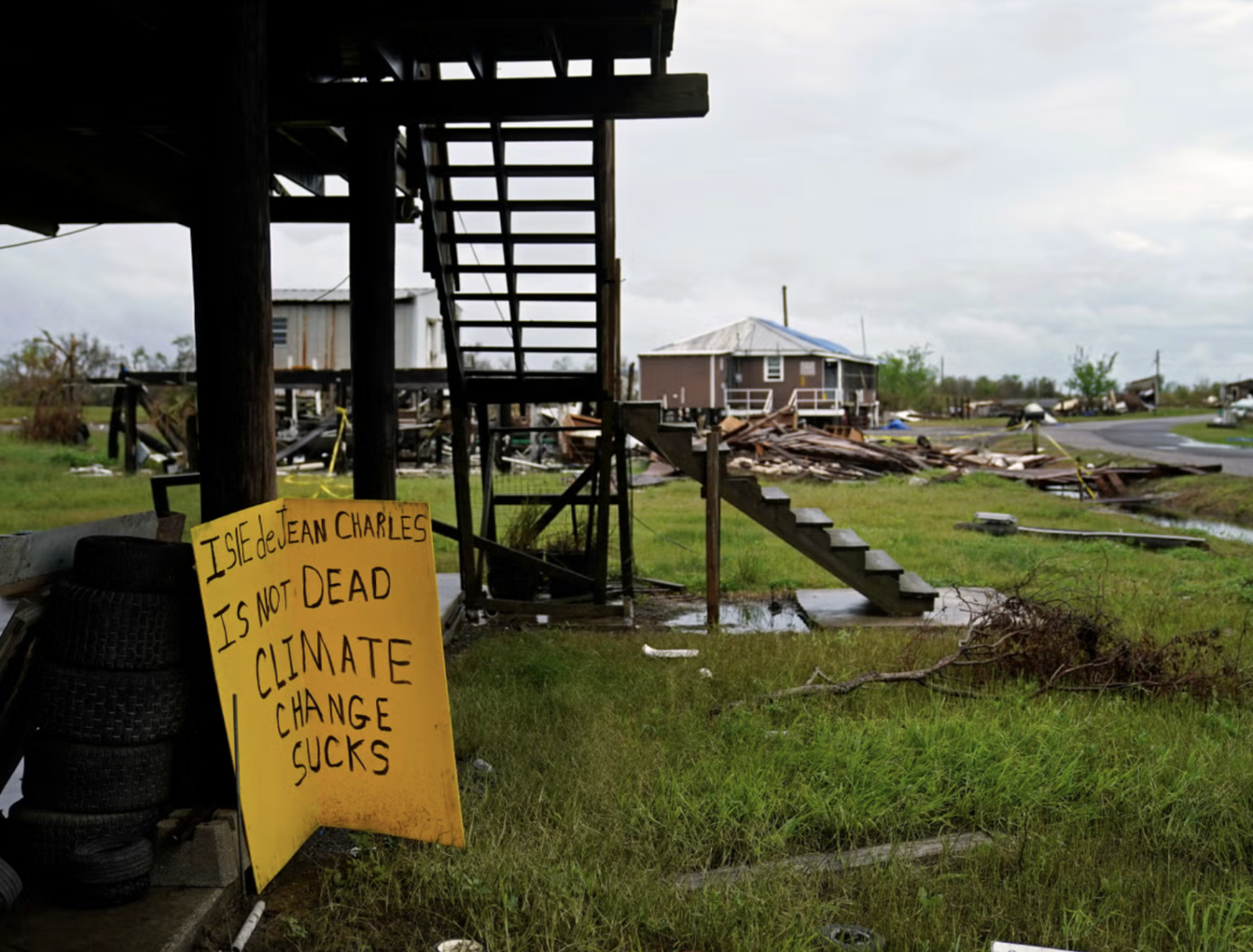 dilapidated structures in a rural setting with a yellow sign