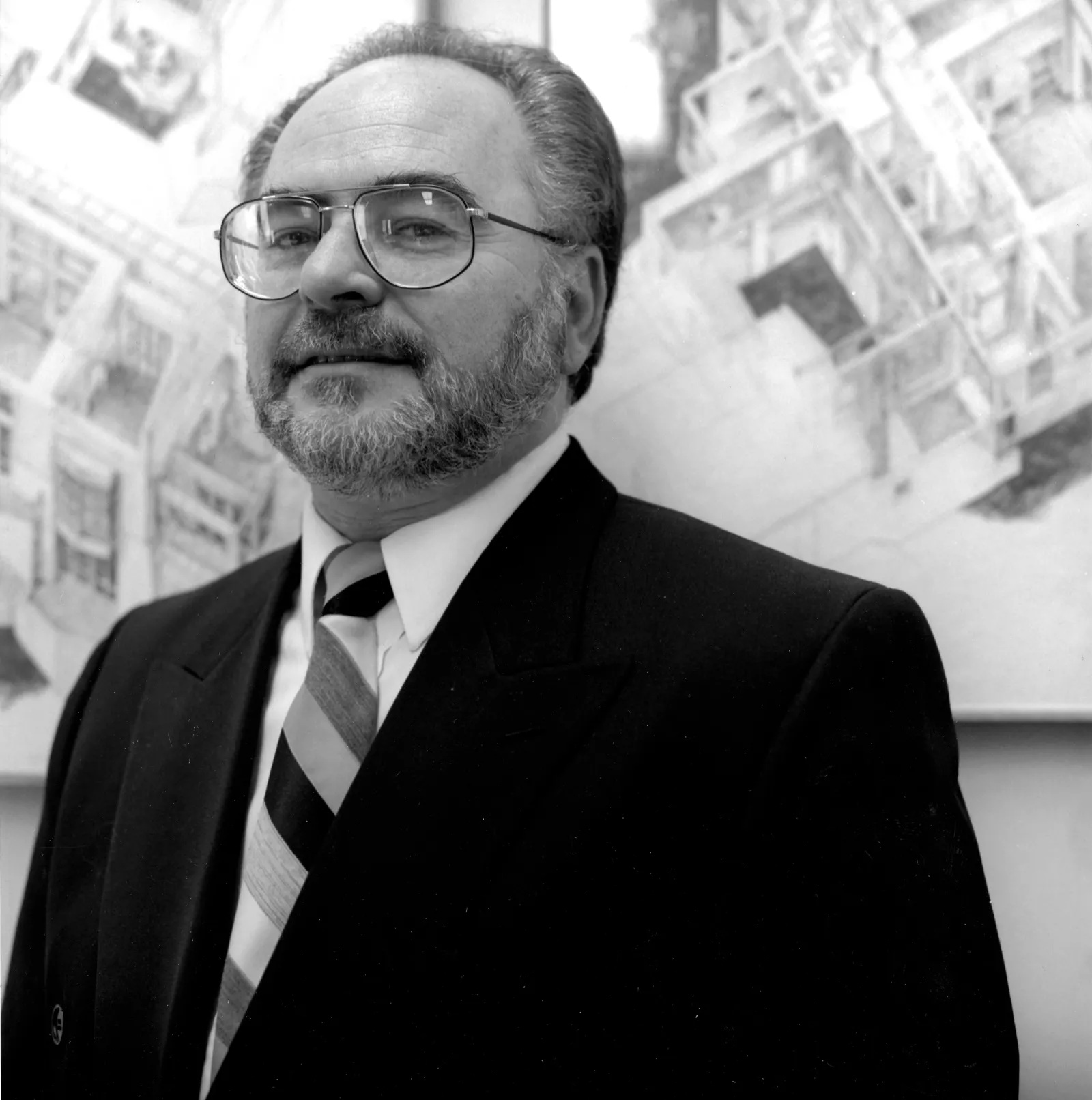 Black and white headshot of a man with a bead wearing glasses