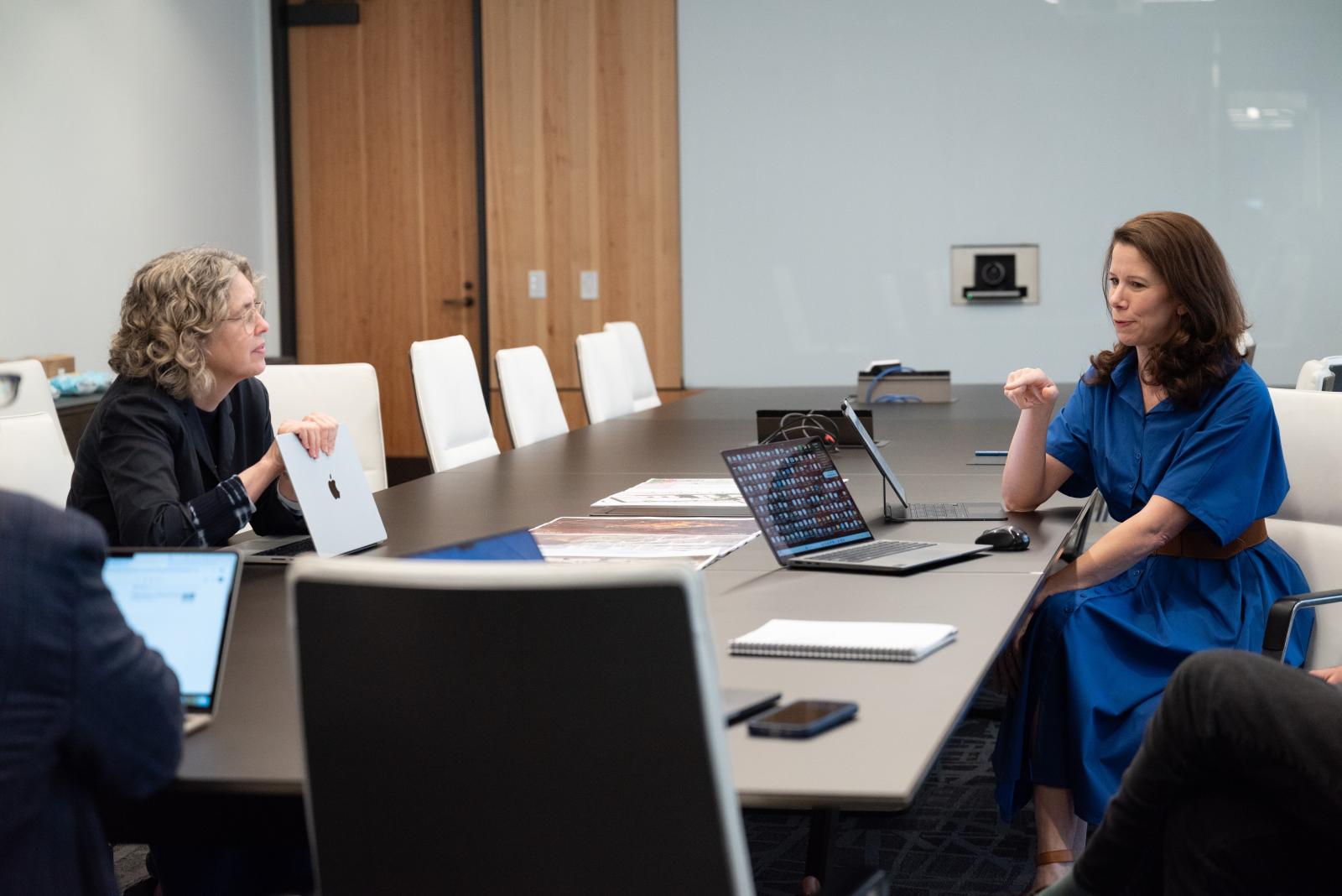 Two women sit and talk to each other at a table. 