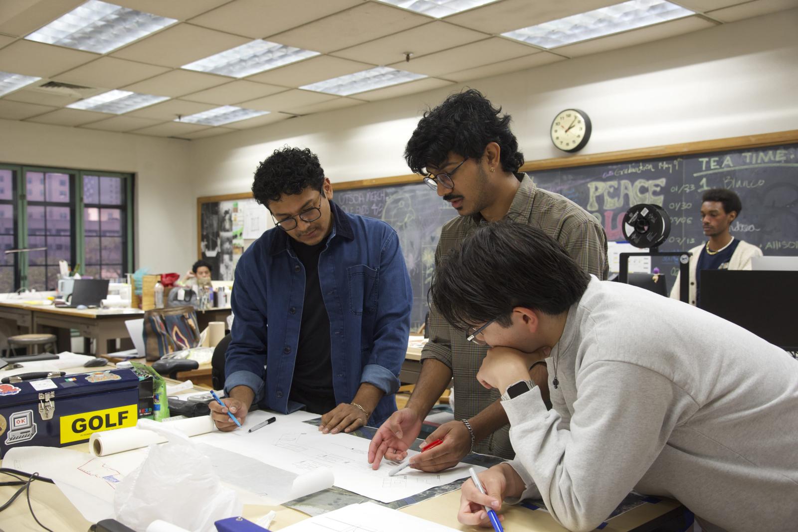 A professor and two students gathered over a work project in studio 