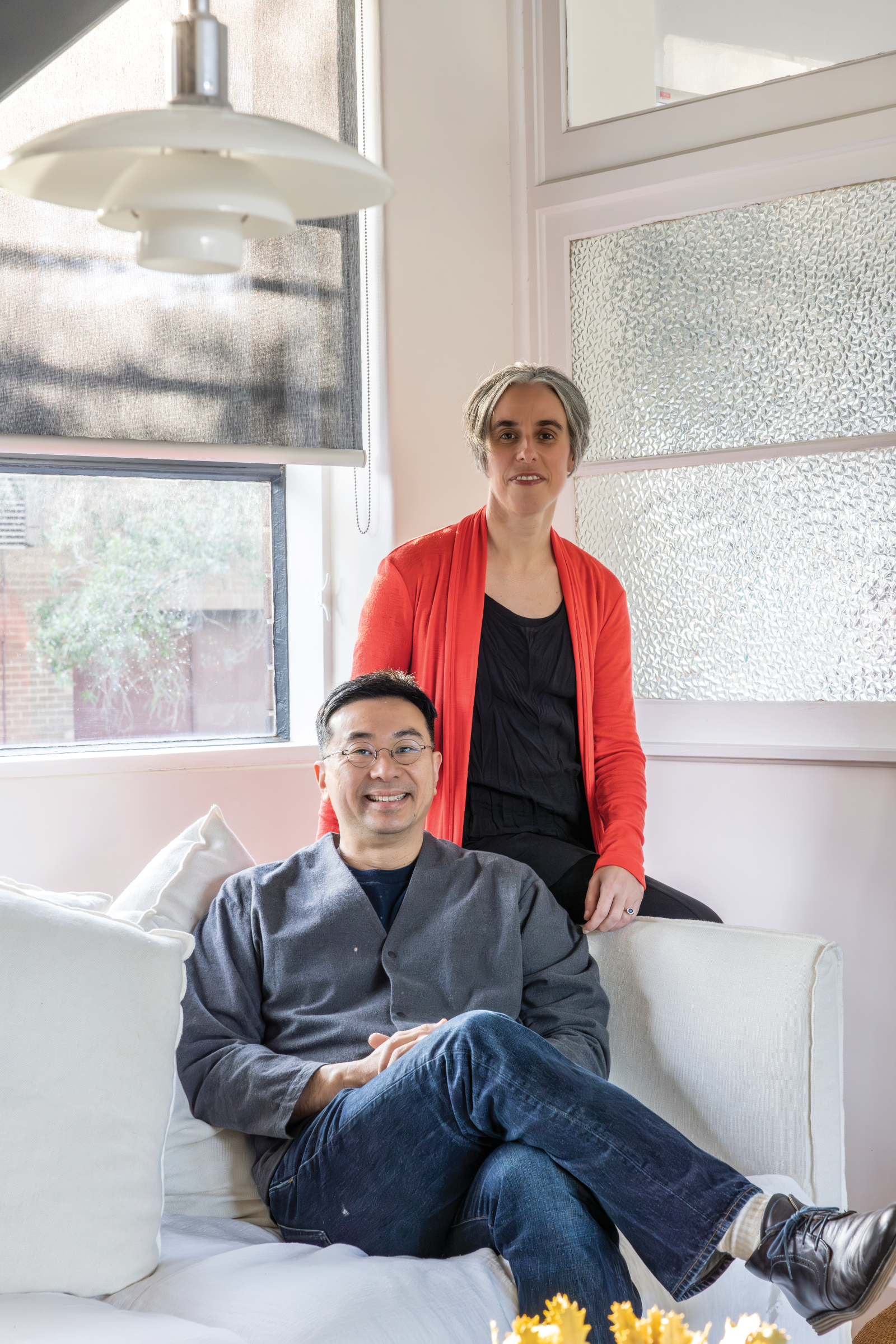 Ken Yeh, seated, and Carol Marra, standing behind him, both in their light-filled home