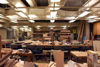 Student stands in a chaotic, messy wood shop