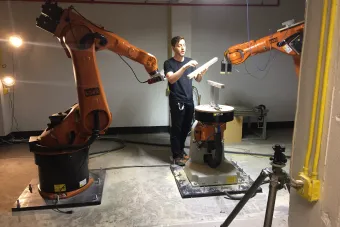 Student interacting with the school's two KUKA robotic arms