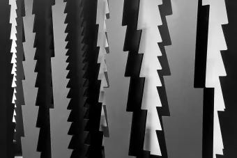 Black and white materials hang from off screen, featuring jagged edges that look like an upside down fir tree