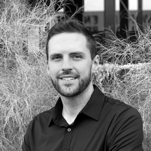 This is a black and white picture of Matt Fajkus standing outside, smiling at the camera.