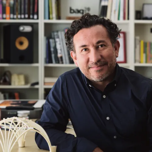 Benjamin Ibarra Sevilla sitting in his office in front of a bookshelf with a 3D-printed object on the desk in front of him