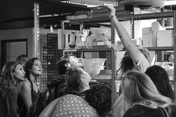 Black and white photo of students looking up at a material sample that someone is holding up to an overhead light