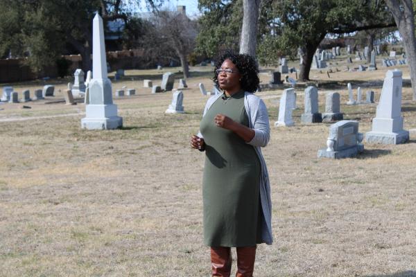 Tara Dudley standing in a cemetery talking animatedly