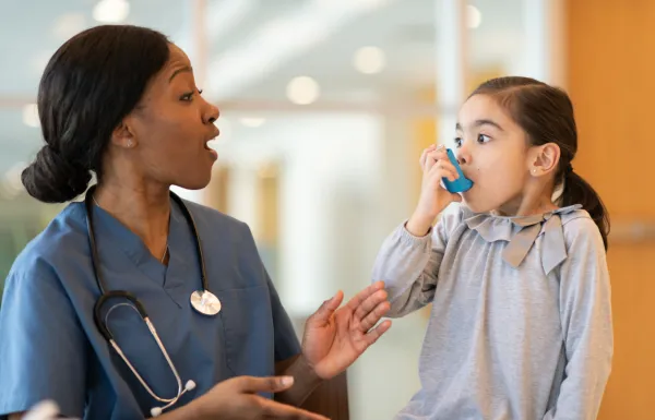 A doctor engaging with a little girl using an inhaler