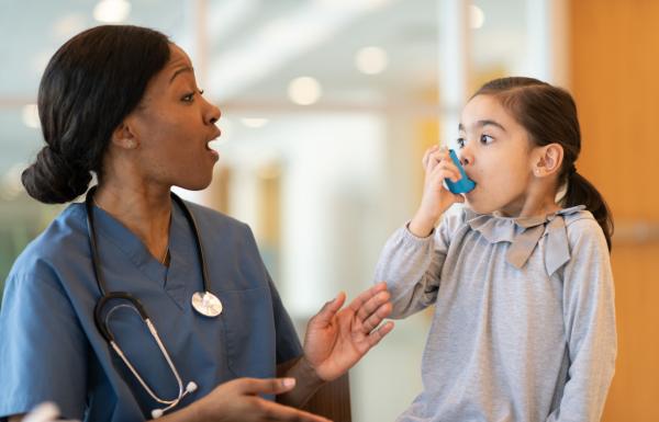 A doctor engaging with a little girl using an inhaler