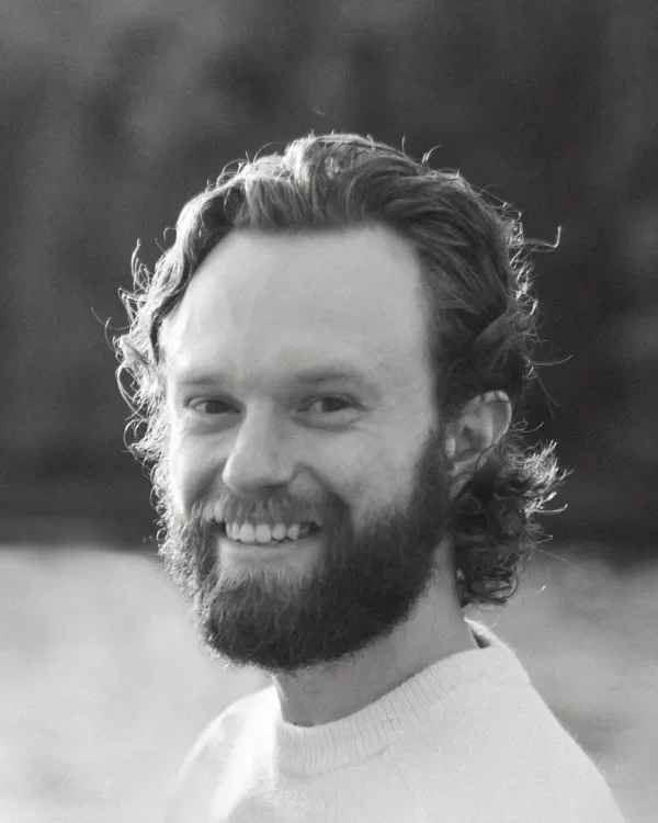 A bearded man smiling at the camera in black and white