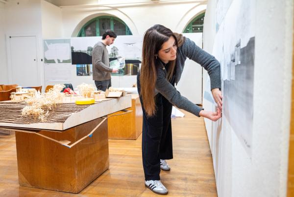 Student pinning work up to a wall