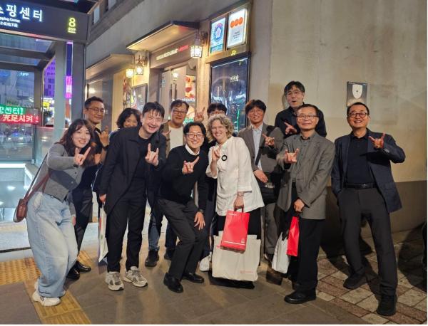 A group of people pose holding up hook em horns hand sign