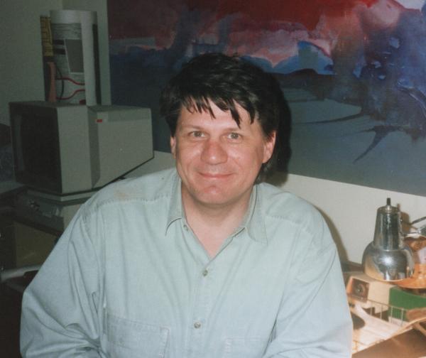 A photo of Michael Garrison in 1992, with one of his paintings in the background