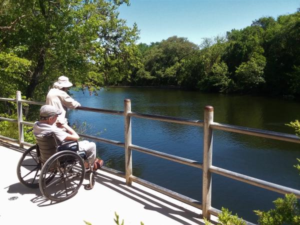 Older couple, one in a wheelchair, looking out onto one of Austin's waterways