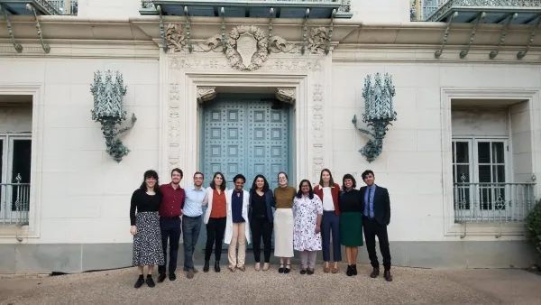 Community & Regional Planning students standing in a line, smiling at the camera in front of one of the blue doors of Battle Hall