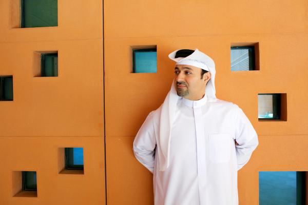Dr. Khaled Alawadi standing next to orange wall