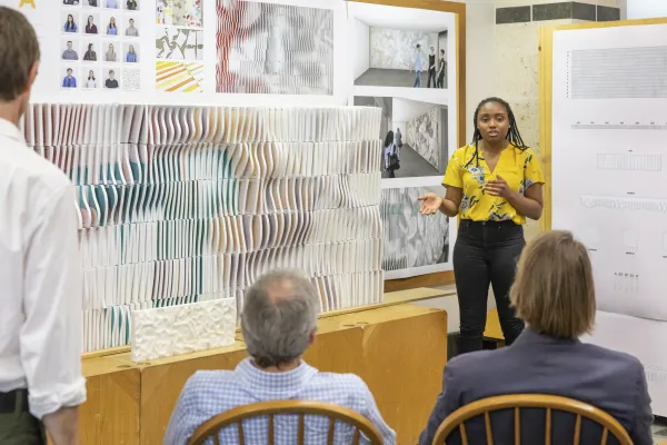 Student gives presentation of ONDA Wall during final reviews to a seated panel