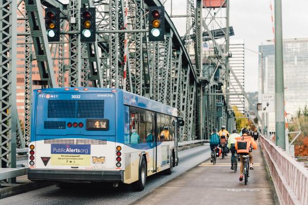 Bicyclists ride alongside a blue bus in downtown Portland