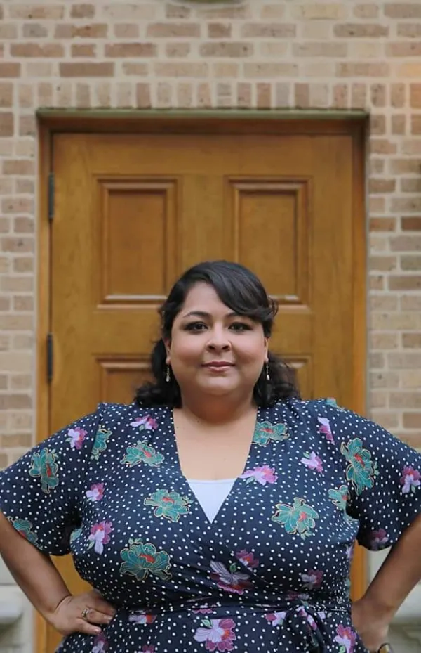 Headshot of Diana Hernadez standing in front of a brick building and wooden door