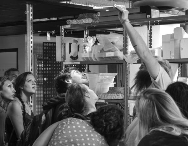 Black and white photo of students looking up at a material sample that someone is holding up to an overhead light