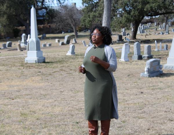 Tara Dudley standing in a cemetery talking animatedly