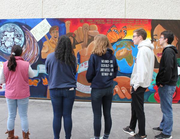 Backs of students seen looking at a colorful mural