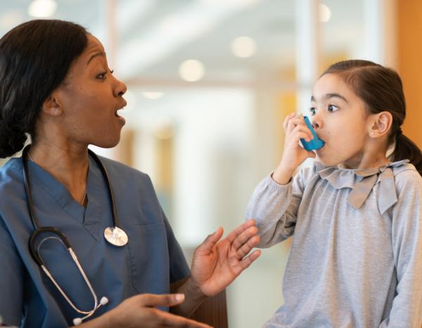 A doctor engaging with a little girl using an inhaler