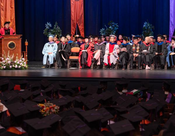 Faculty wearing regalia on stage at commencement